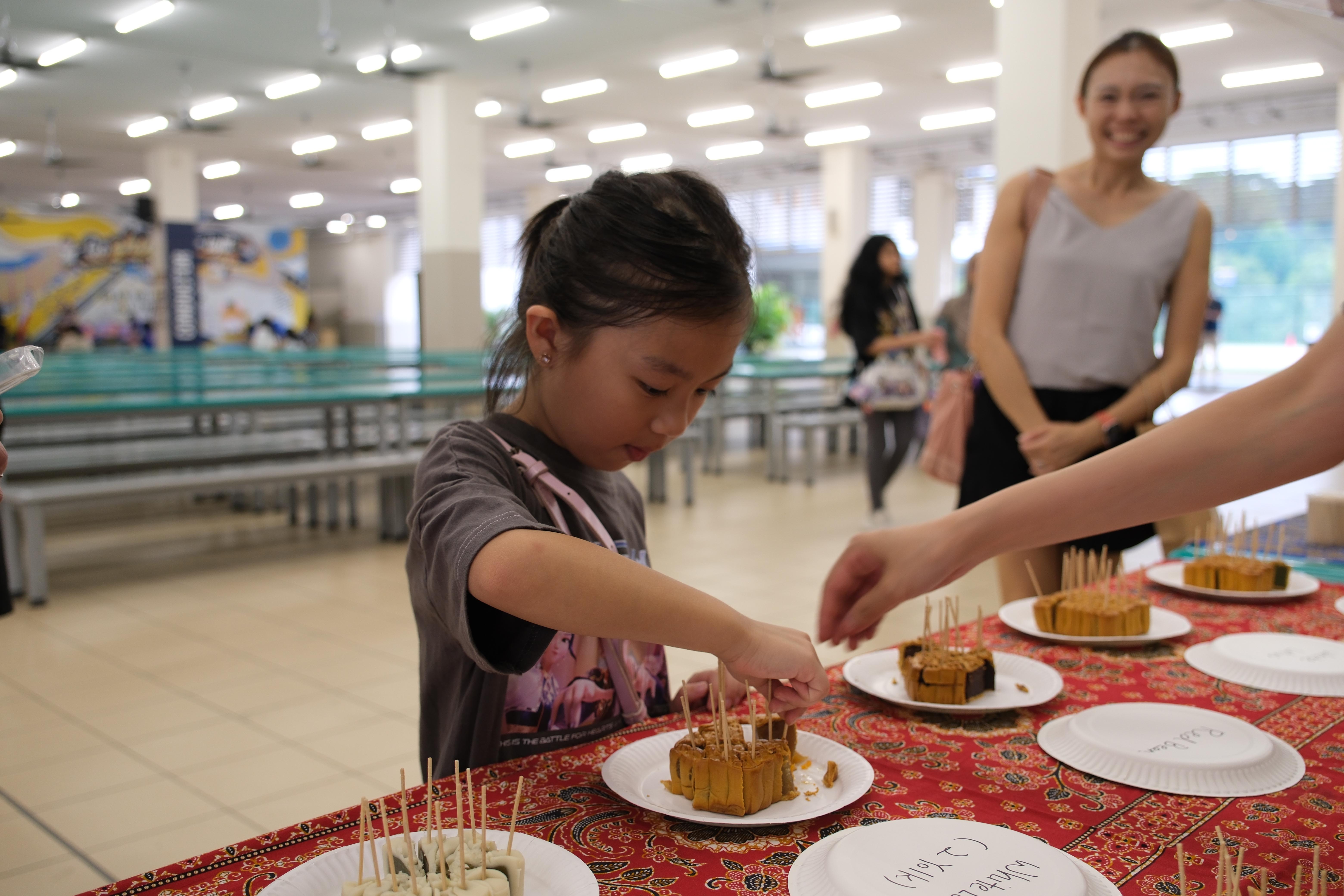 Getting a taste of tradition! Student eagerly samples the delicious mooncakes prepared for the celebration.